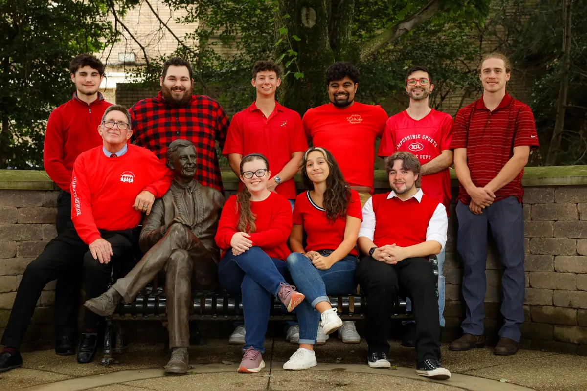 The West Media Group team, all in red, gathered around the Fred Rogers statue in their hometown of Latrobe, Pennsylvania.